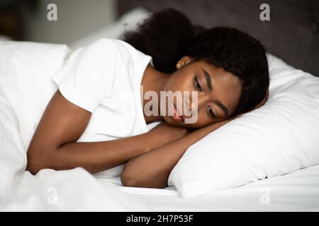 Verärgerte afroamerikanische Dame, die allein im Bett lag Stockfoto