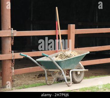 Eine Schubkarre in einem Pferdestall, die zum Ausrüsten verwendet wurde. Stockfoto