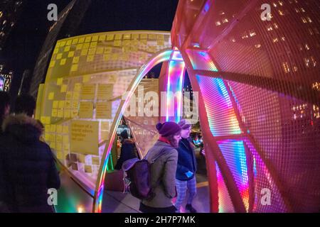 Besucher des Flatiron Plaza in New York am Montag, den 22. November 2021, interagieren mit „Interwoven“, das von Atelier Cho Thompson geschaffen wurde. Die Weihnachtsinstallation ist das Herzstück des Weihnachtsprogrammierens der Flatiron/23rd Street Partnership, „23 Tage Flatiron jubeln“. „Interwoven“ ist eine erfahrungsmäßige Skulptur, bei der Licht und Musik gespielt werden, wenn die Besucher durch die Sensoren des Stückes gehen. (© Richard B. Levine) Stockfoto