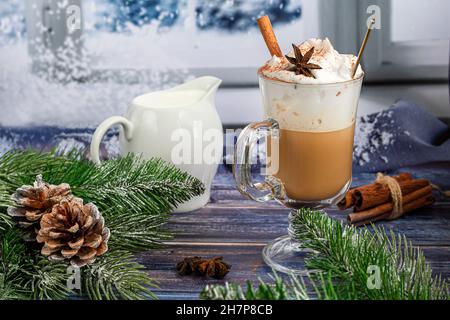 Heißer Kaffee Latte mit Zimtstangen, mit Zimt bestreut. Weihnachtsschmuck, Zweige eines Weihnachtsbaums. Weihnachtskonzept Neujahr. In einem Arbeitsauftrag Stockfoto