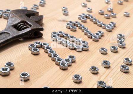 Die Nummer 2022 ist auf einem Holztisch neben einem großen, alten Schraubenschlüssel mit Metallmuttern ausgekleidet. Konzept der Vorbereitung auf das neue Jahr. Stockfoto