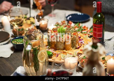 Nahaufnahme verschiedener köstlicher Vorspeisen und einer Flasche Rotwein auf einem festlichen Esstisch Stockfoto