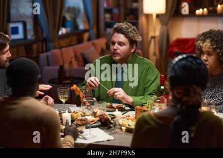 Eine Gruppe von Freunden, die während einer Dinnerparty miteinander reden, während sie am Tisch essen Stockfoto