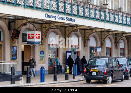 Schwarze Londoner Taxis und Passagiere auf dem Vorplatz der Charing Cross Station am Strand, London, Großbritannien Stockfoto