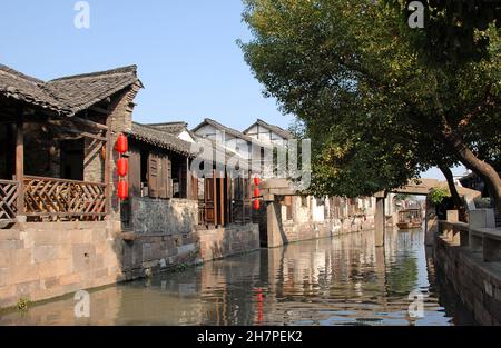 Wuzhen Water Town, Provinz Zhejiang, China. Ein traditionelles Holzgebäude mit roten Laternen an einem Kanal in der alten chinesischen Stadt Wuzhen. Stockfoto