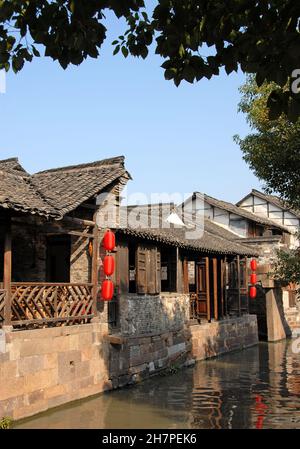 Wuzhen Water Town, Provinz Zhejiang, China. Ein traditionelles Holzgebäude mit roten Laternen an einem Kanal in der alten chinesischen Stadt Wuzhen. Stockfoto