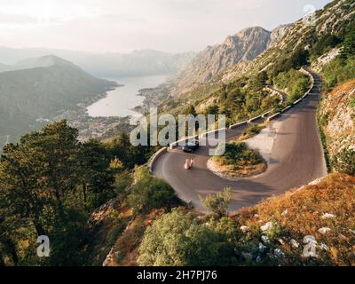 Braut und Bräutigam laufen entlang einer Bergstraße vor dem Hintergrund der Kotor Bay. Drohne Stockfoto