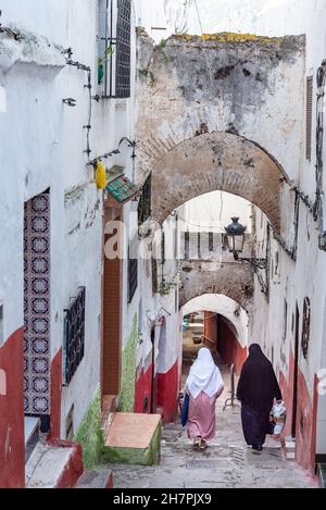 In der Medina von Tetouan in Marokko. Zwei Frauen, die einen Schleier tragen, gehen durch eine der steilen Gassen der Medina Stockfoto