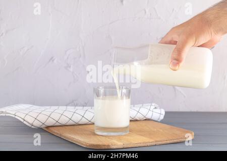 Mann Hand gießt Milch aus dem Glas in Trinkglas in der Küche zu Hause Stockfoto