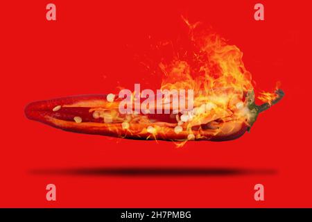 Rote, scharfe Chilischote auf Feuer, in zwei Hälften geschnitten, mit Samen aus nächster Nähe, die auf einem roten Hintergrund schweben Stockfoto