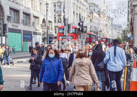 Menschen, die während der Coronavirus-Pandemie auf einer belebten Oxford Street Schutzmasken tragen. London, Großbritannien, 26. Oktober 2021. Stockfoto