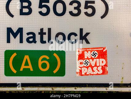 Kein Covid Pass-Aufkleber mit Hakenkreuz auf einem Straßenschild in der Nähe von Matlock im Derbyshire Peak District England Großbritannien während der Coronavirus-Pandemie von 2021. Stockfoto