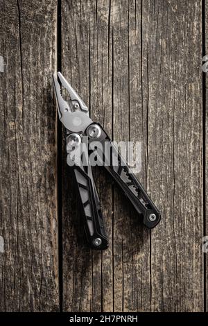 Multi-Tools-Zange mit anderen Werkzeugen und Messer. Multifunktionszange auf Holztisch. Draufsicht. Stockfoto