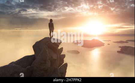 Abenteuerliche Frau auf einem Rocky Mountain mit Blick auf die Küste. Stockfoto