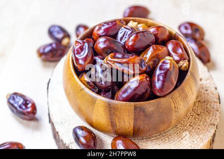 Süße getrocknete Datteln in einer runden Holzschale auf hellem Hintergrund in der Küche. Stockfoto