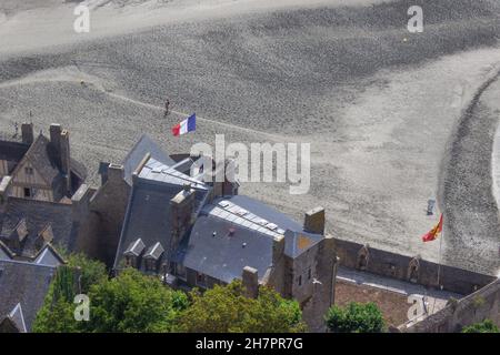 Blick von oben auf die Dächer von Mont Saint michel, Normandie, Frankreich, französische Flagge weht im Wind. Stockfoto