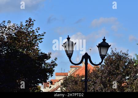 Eine antike Lampe an einem blauen Himmel, die neben einem historischen Gebäude steht. Stockfoto