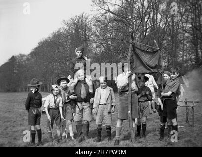 1939, historisches Pfadfinderlager, weibliche Pfadfindermeisterin mit einer Gruppe von jungen Pfadfindern auf dem Feld, al in Uniform, aber einige verkleidet, die einen kommunistischen Umzug abgewiesen haben, England, Großbritannien. Stockfoto