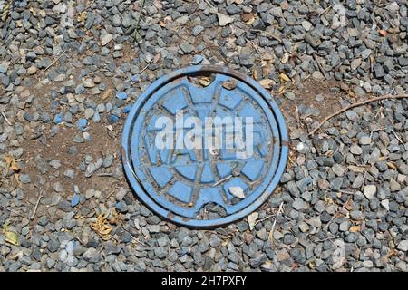 Blaue Metallwasserabdeckung im Boden. Stockfoto