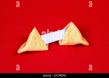 Frisch gebackene gelbe chinesische Glückskekse mit weißer, leerer Note auf rotem Hintergrund. Stockfoto