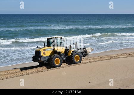 Ein Traktor transportiert einen großen Felsen zum Bau einer Ufermauer. Stockfoto