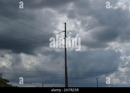 Hochspannungsleitungen durchziehen den bewölkten Himmel. Stockfoto