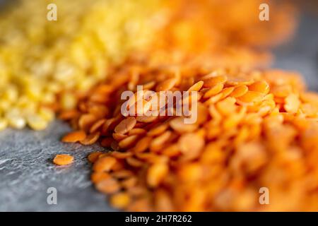 Rote und gelbrote Linsen vor grauem Hintergrund, mit selektivem Fokus Stockfoto