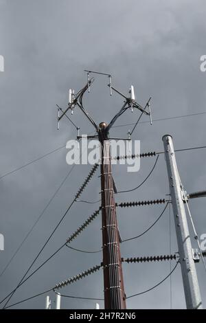 Nahaufnahme der Oberseite eines hohen Zellturms mit Hochspannungsleitungen. Stockfoto