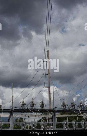 Massive Hochspannungsleitungen erstrecken sich über ein elektrisches Umspannwerk. Stockfoto