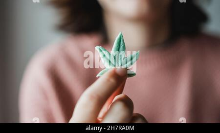 CBD-Süßigkeiten - Frau mit essbarem Cannabisblatt zur Angstbehandlung - Marihuana alternative Medizin Stockfoto