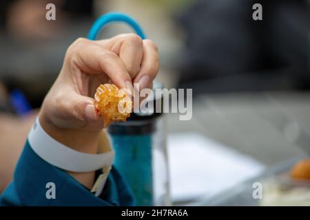 Übergewichtige Frau, die Knödel isst. Person, die Süßigkeiten in der Hand hält Stockfoto
