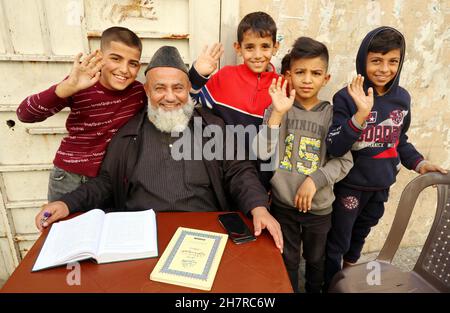 Ein sufi-islamischer Lehrer gibt einer Gruppe syrischer Kinder am 24. November 2021 in einer Straße in Beirut, Libanon, Unterricht. Am 23. November stellte UNICEF den Bericht „ohne die Grundlagen überleben; die sich immer weiter verschärfenden Auswirkungen der Libanonkrise auf Kinder“ vor. Der Bericht basiert auf zwei Erhebungen, die von UNICEF im April 2021 und erneut im Oktober 2021 unter denselben Familien durchgeführt wurden.der Bericht vom November 22 zeigt einen Anstieg der Zahl der hungernden Kinder, die arbeiten müssen, um ihre Familie zu unterstützen, Nicht zur Schule gehen und nicht die Gesundheitsversorgung bekommen, die sie brauchen. Die Zahlen zeigen eine dramatische Verschlechterung Stockfoto