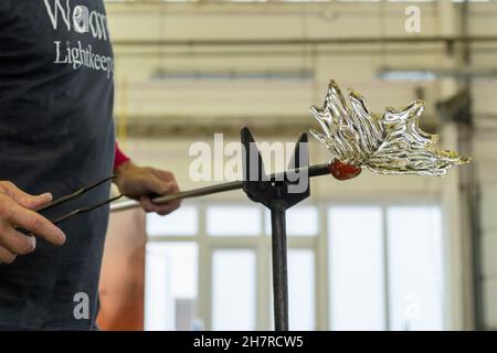 Nahaufnahme Mann macht ein Blatt aus dem Glas für Vase oder Kronleuchter mit Zange und Blasrohr. Stockfoto