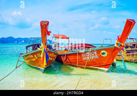 Schöne bunte Longtail Boote, die am Strand der Andamanensee in der Region Krabi, Thailand, festgemacht sind Stockfoto