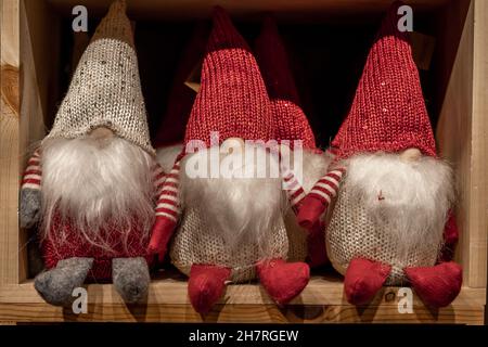 Drei Weihnachtszwerge mit langen weißen Bärten, die auf dem Regal sitzen. Stockfoto