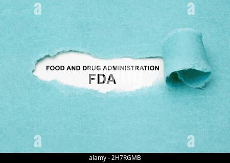 Gedruckter Text FDA Food and Drug Administration erscheint hinter zerrissenem blauem Papier. Stockfoto