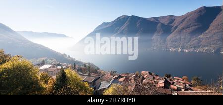Die Stadt Nesso im Herbst am Ufer eines nebligen Comer Sees in Norditalien Stockfoto