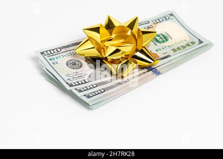 Geldgeschenk von 100 Dollar Scheinen mit Goldbogen. Geschenksteuer, wohltätige Spende und Weihnachtsgeschenk Konzept. Stockfoto