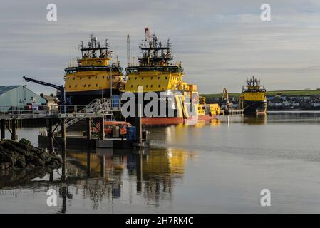 Drei „Viking“ Anchor Handling Schlepper Supply (AHTS)-Schiffe, die am Montrose Harbour in Schottland anliegen, sahen sich im Abendlicht mit Reflexionen im Wasser an. Stockfoto