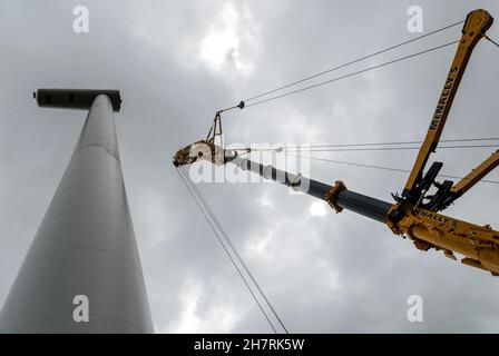 Blick von der Basis eines Windenergieanlagenturms vor der Installation der Rotorblätter mit erweitertem Kranausleger, um die Rotorbaugruppe anzuheben. Stockfoto