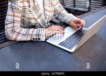 Beschnittene Ansicht des Büromitarbeiters, der am Tisch im Café sitzt. Weibliche Hände geben Text auf dem Tastenfeld des Laptops ein Stockfoto