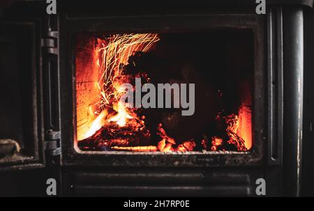 Feuer brennend glühend im rustikalen Holz brennenden Gusseisen-Ofen, Holzbrenner zum Heizen oder Kamin Stockfoto