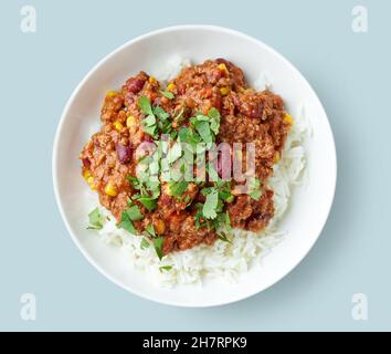 Teller mit Reis und Chili con Carne isoliert auf blauem Hintergrund, Draufsicht Stockfoto