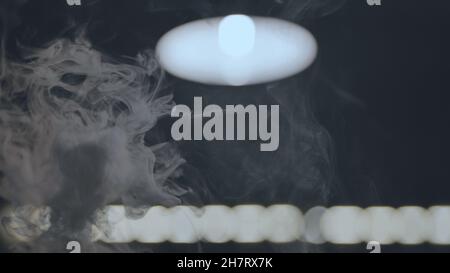 Der aufsteigende Rauch in der Shisha Bar vor dem Hintergrund der Lampe. Stockfoto