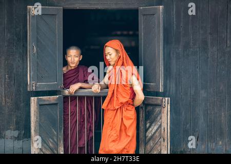 Buddhistische Mönche in Kesaya-Bademänteln orange und rot (Kesa) im Bagaya-Teak-Kloster, Inwa, Mandalay Region, Myanmar Mönch buddhismus Bildfoto Stockfoto