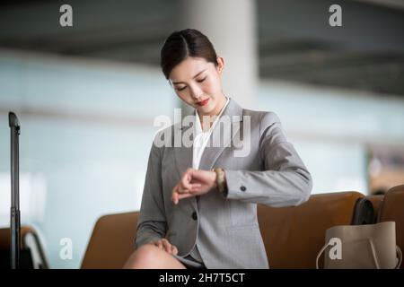 Junge Geschäftsfrau, die ihre Uhr in der Flughafenlounge anschaut Stockfoto