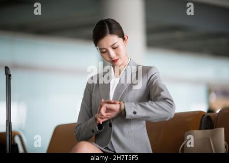 Junge Geschäftsfrau, die ihre Uhr in der Flughafenlounge anschaut Stockfoto