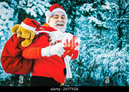 weihnachtsmann mit großer Tasche. Weihnachtsmann mit Tasche zu Fuß im Winter im Freien. Stockfoto