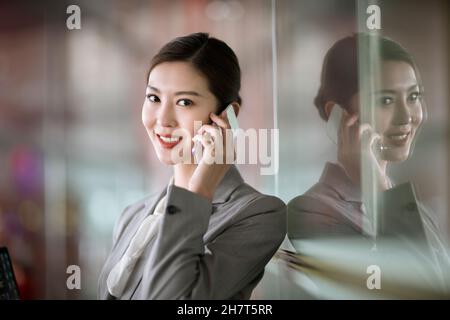 Junge Geschäftsfrau, die in der Flughafenlounge telefoniert Stockfoto