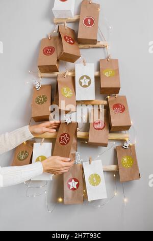 Hängen DIY handgefertigten Handwerk Weihnachten Adventskalender mit Geschenken. Mutter bereitet festliche Einrichtung und Tradition für Kinder vor. Taschen mit Datteln auf Öko Baum Stockfoto